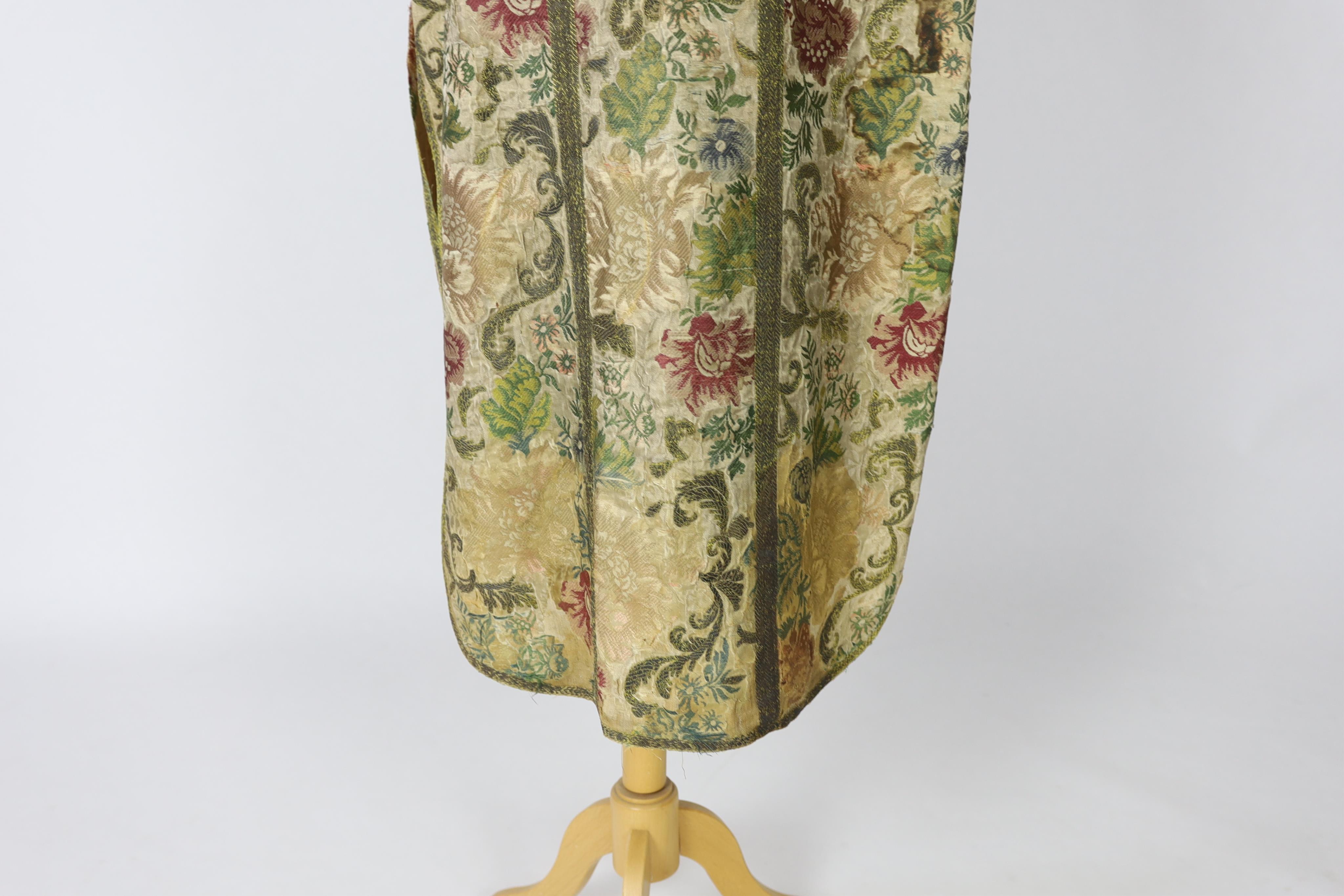 A late 18th century continental, possibly French, silk multi coloured and metallic brocade chasuble, lined with thick linen, edged and panelled with a thick metallic braid, 99cm long